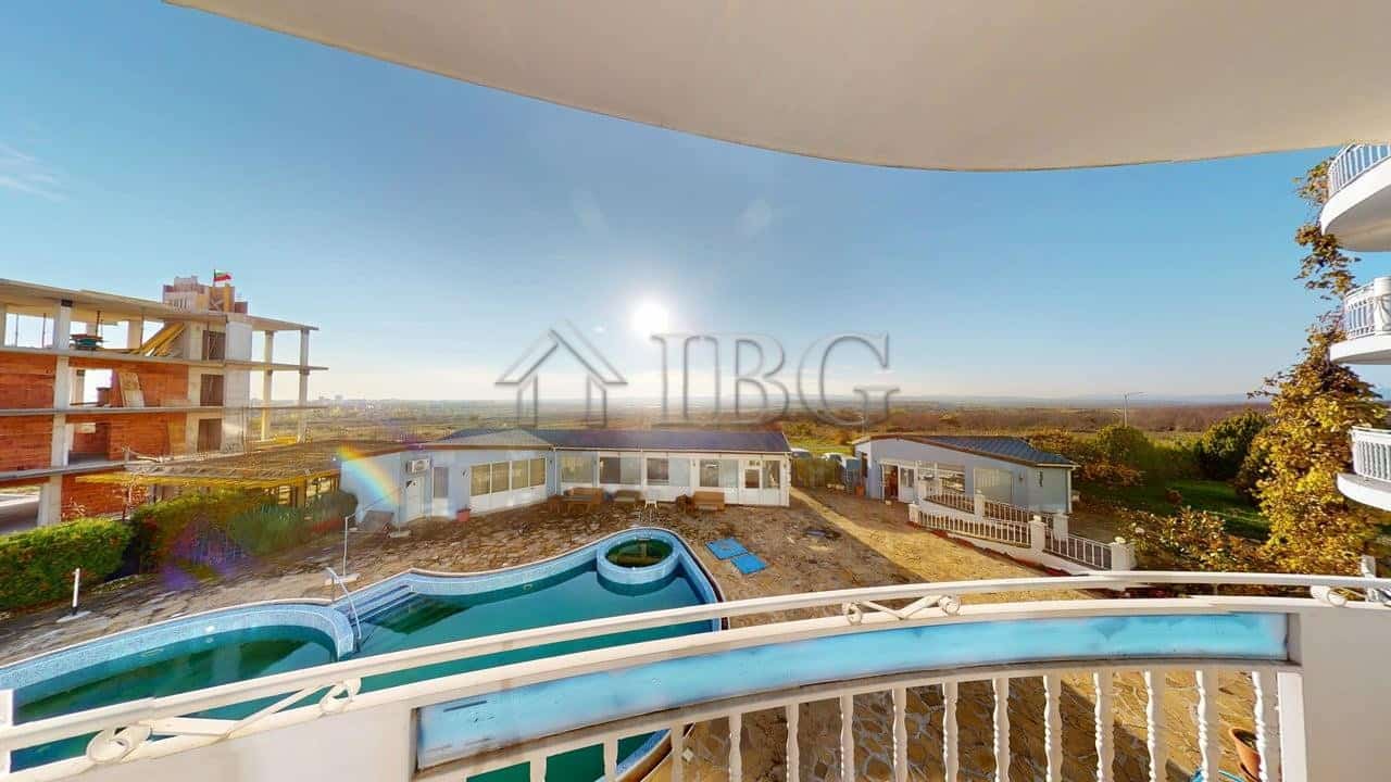 Modern balcony overlooking Rio apartments, pool, and surrounding cityscape with clear blue sky.