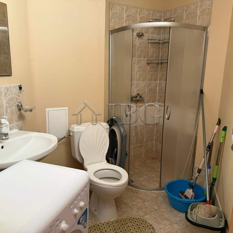 Bright bathroom with shower cabin and washing area.