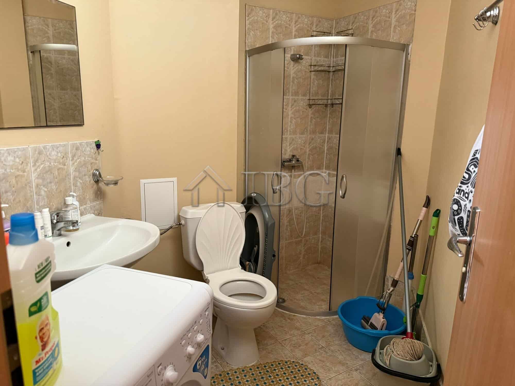 Bright bathroom with shower cabin and washing area.