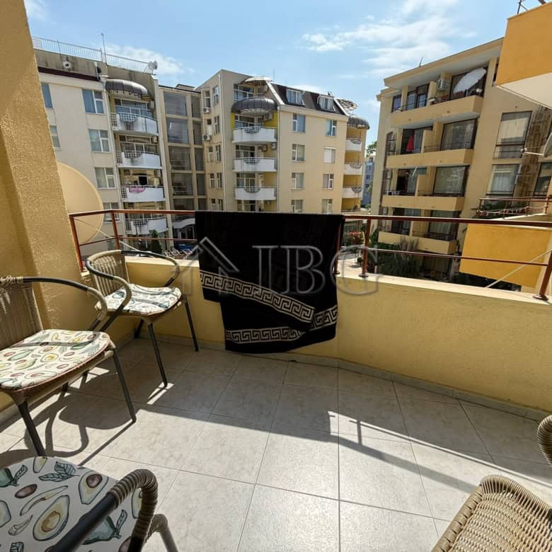Balcony of a 2-bedroom apartment with seating, overlooking Sunny Beach buildings and blue sky.