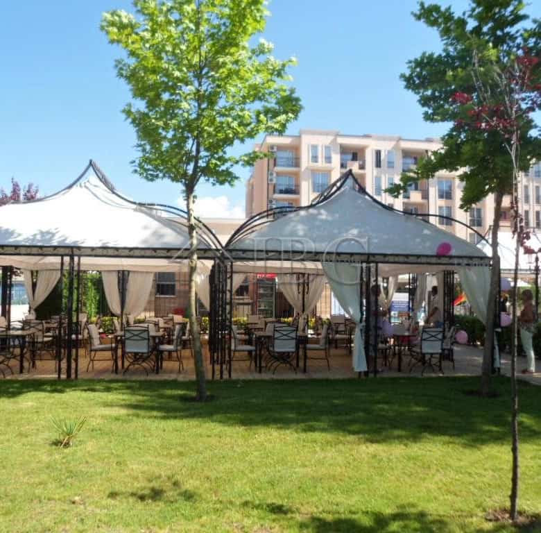 Outdoor dining setup with tents and tables in a sunny beach location.