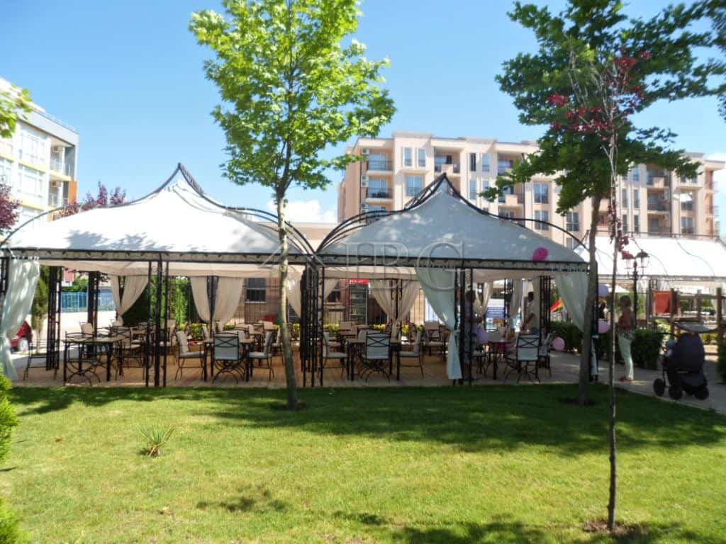 Outdoor dining setup with tents and tables in a sunny beach location.