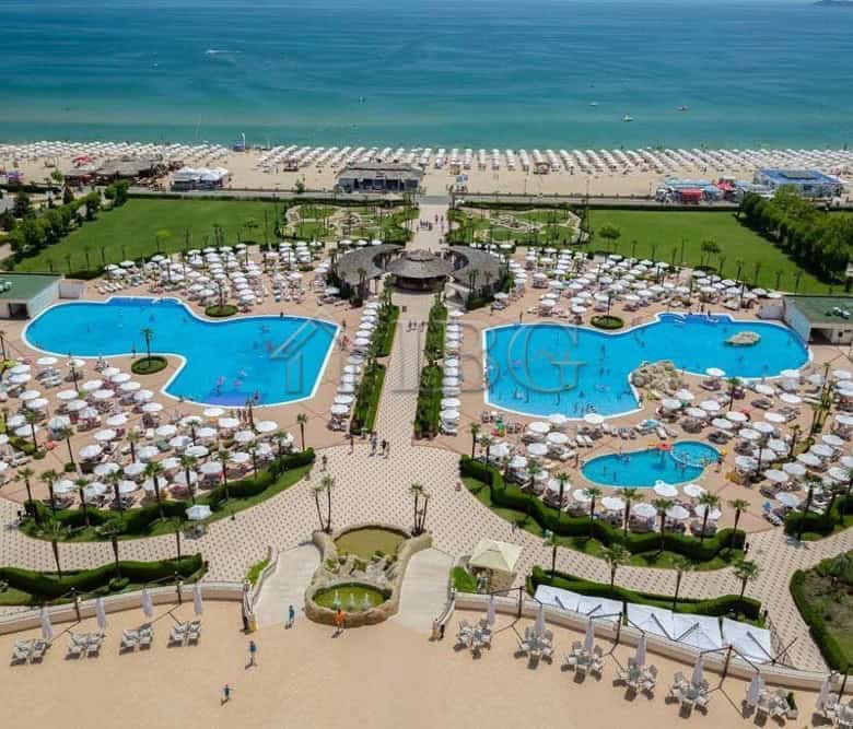 Beautiful view of the resort's two large swimming pools with sun loungers and umbrellas, overlooking.