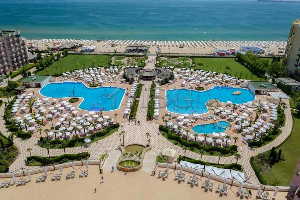 Beautiful view of the resort's two large swimming pools with sun loungers and umbrellas, overlooking.