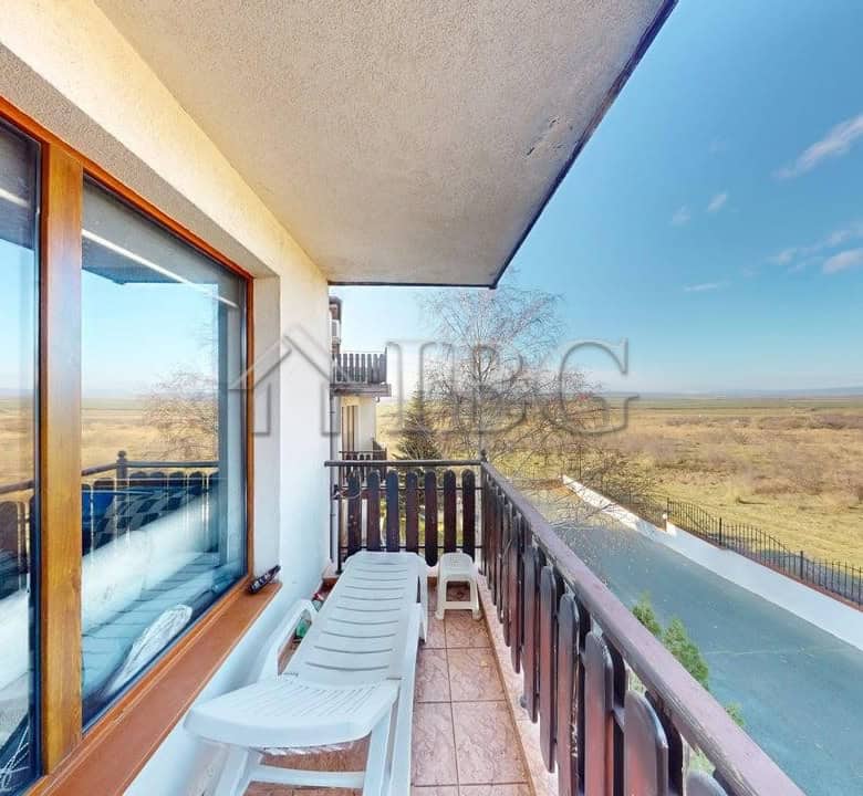 Balcony of a two-bedroom apartment overlooking open fields and a clear blue sky in Kosharitsa.