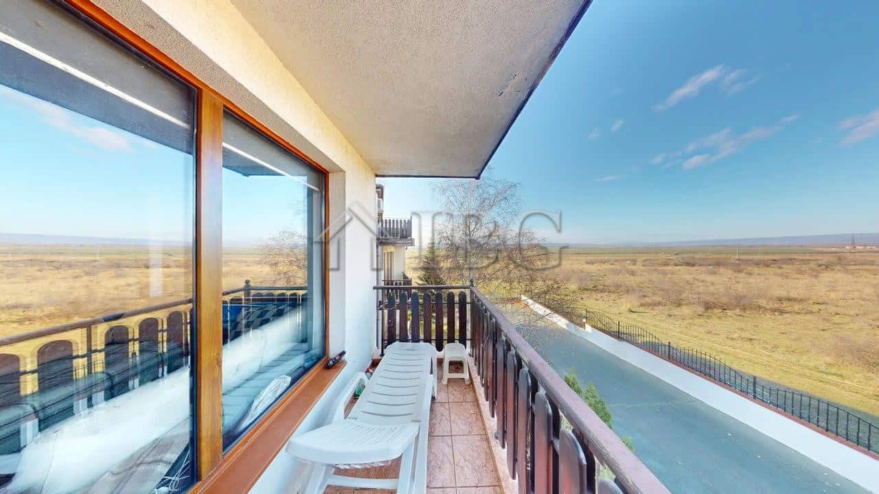 Balcony of a two-bedroom apartment overlooking open fields and a clear blue sky in Kosharitsa.