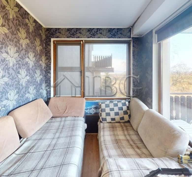 Bright living room with large windows and balcony view in Kosharitsa apartment.
