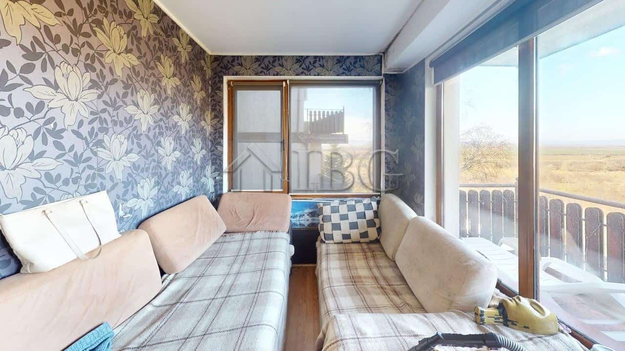 Bright living room with large windows and balcony view in Kosharitsa apartment.
