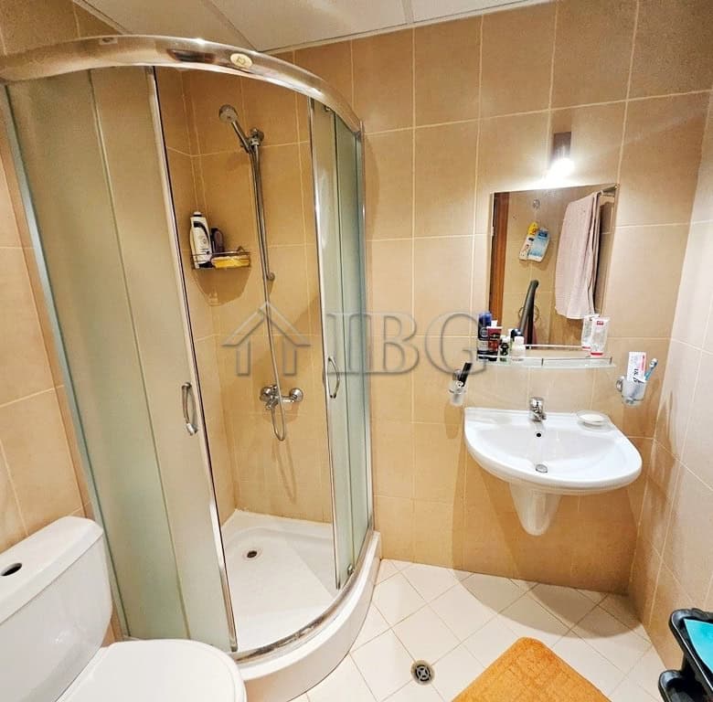 Bathroom with shower, sink, and toilet in a sunny beach apartment.