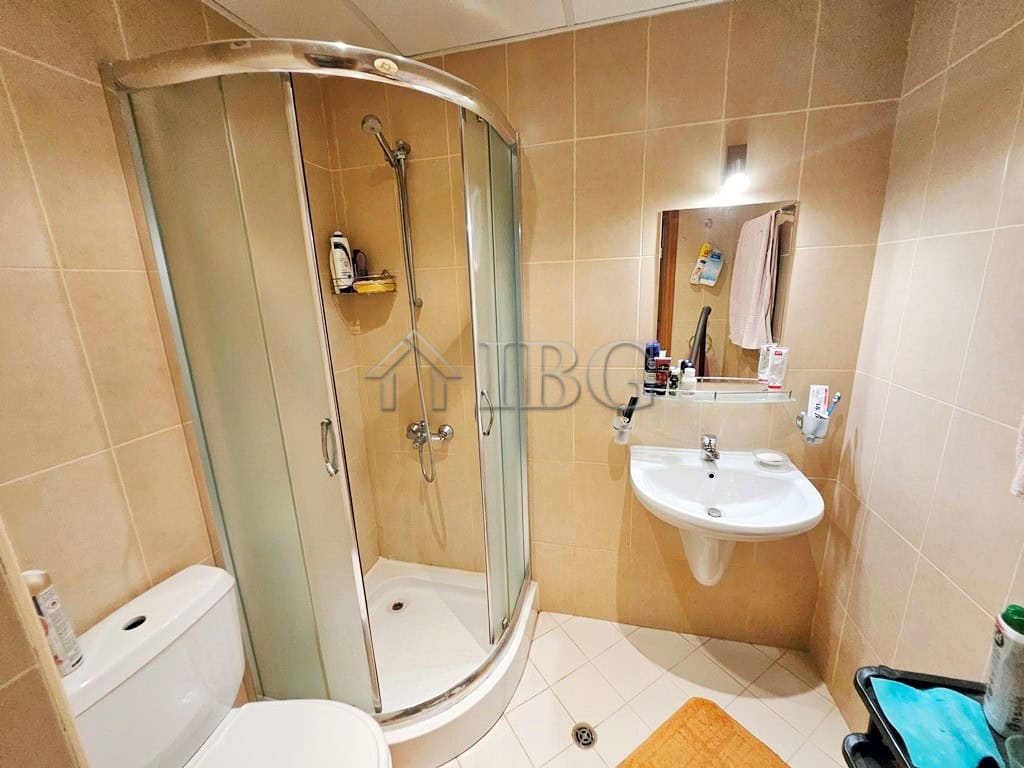 Bathroom with shower, sink, and toilet in a sunny beach apartment.