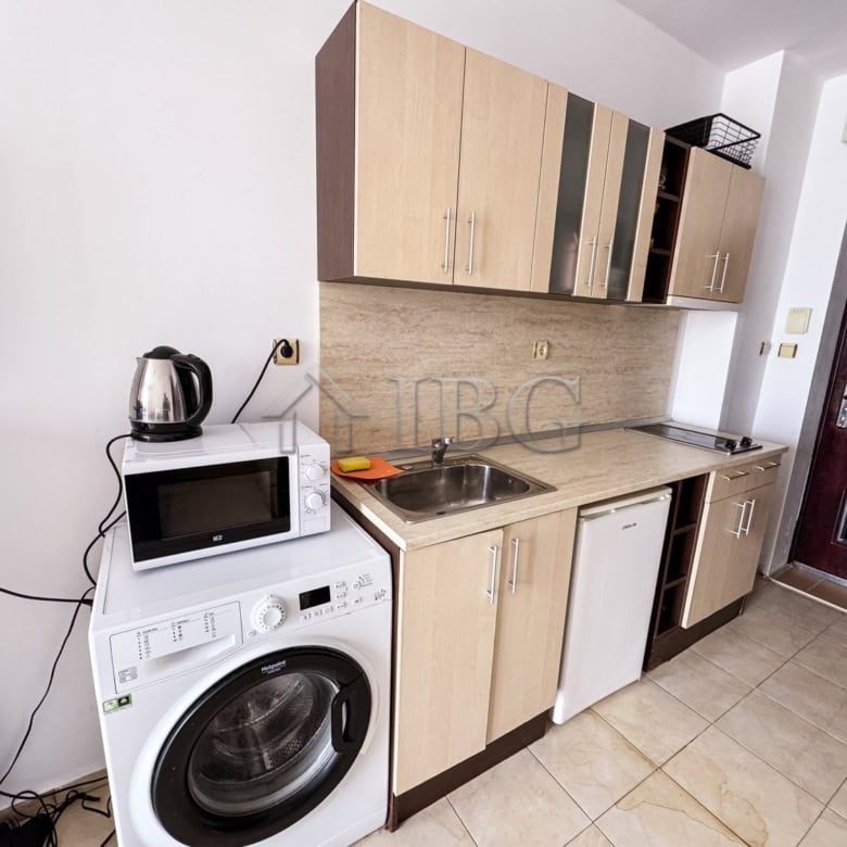 Cozy studio kitchen featuring a washing machine, microwave, and compact fridge, with a pool view in.