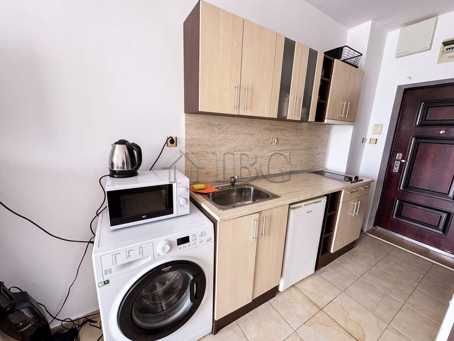 Cozy studio kitchen featuring a washing machine, microwave, and compact fridge, with a pool view in.