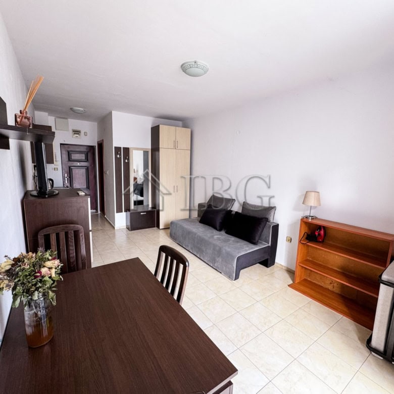 Interior of a cozy studio apartment with pool view, featuring a sofa, dining table, and modern decor.
