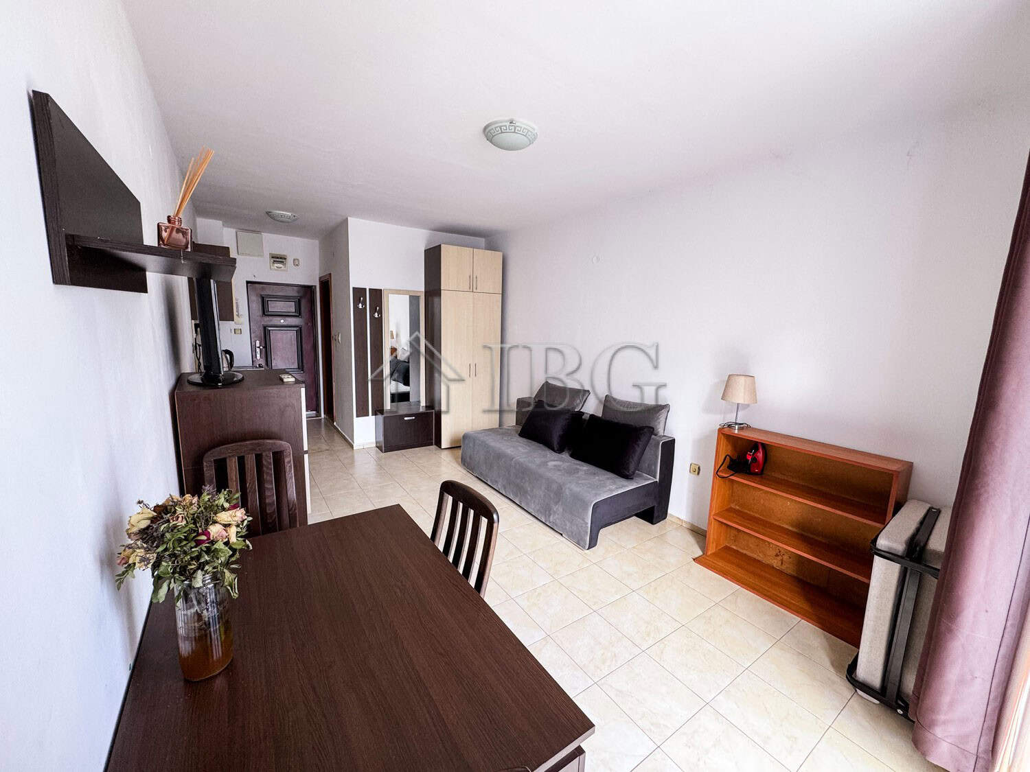 Interior of a cozy studio apartment with pool view, featuring a sofa, dining table, and modern decor.