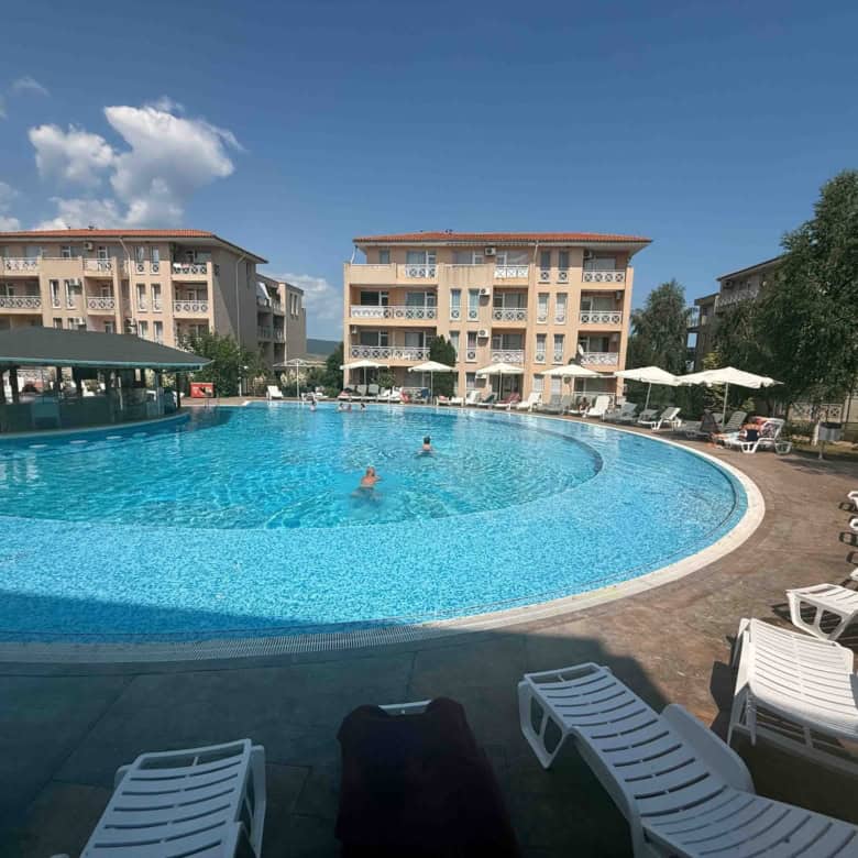 Pool view of modern apartments near Sunny Beach with outdoor swimming pool and sun loungers.