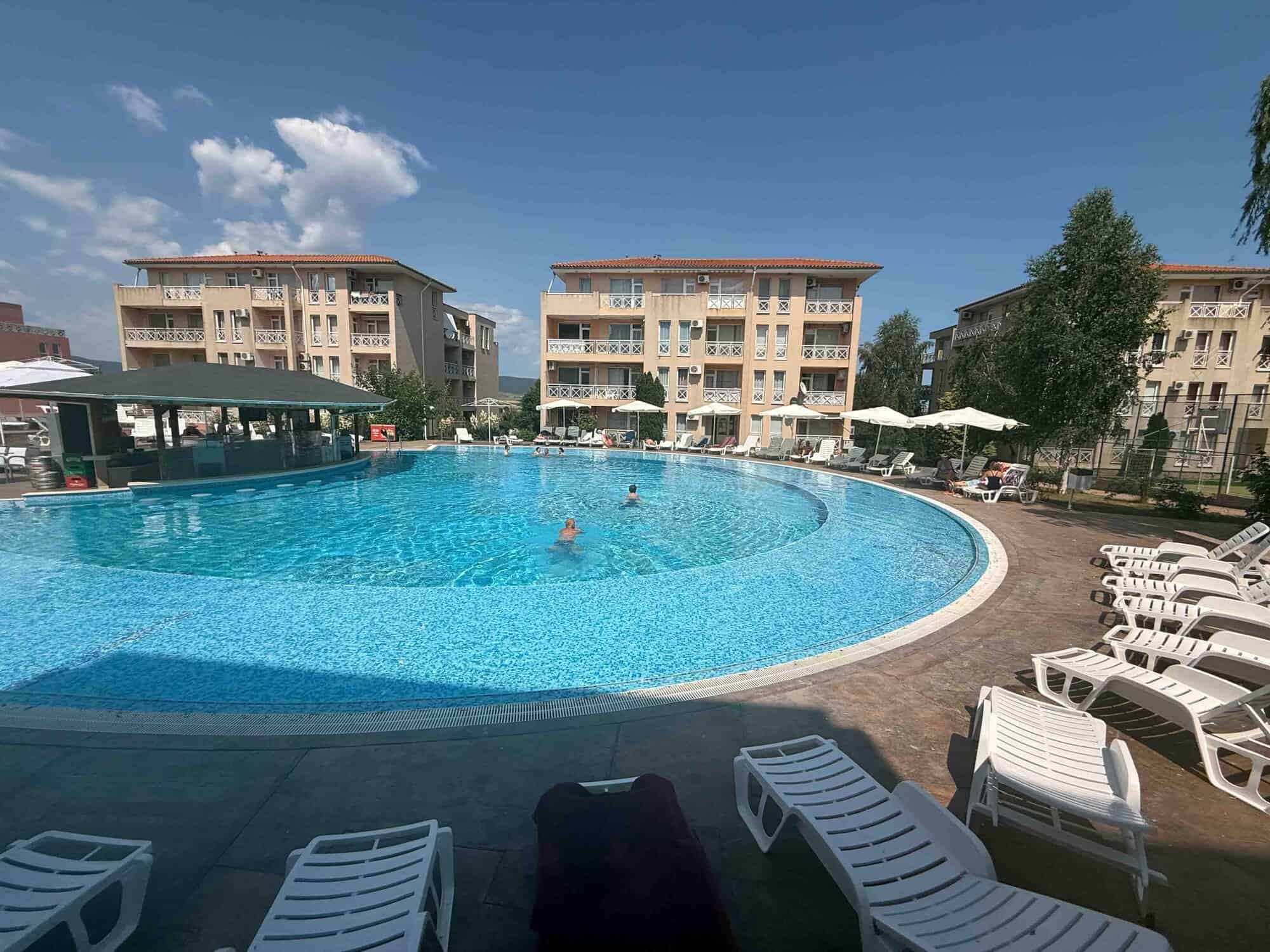 Pool view of modern apartments near Sunny Beach with outdoor swimming pool and sun loungers.