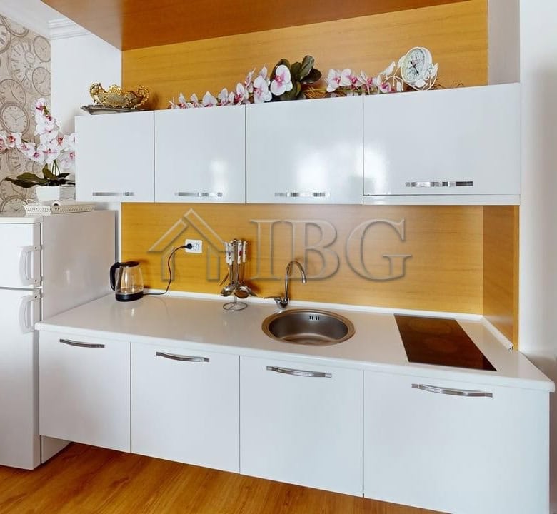 Bright, modern kitchen in Sunny Beach apartment with 2 rooms, featuring white cabinets and wooden ac.