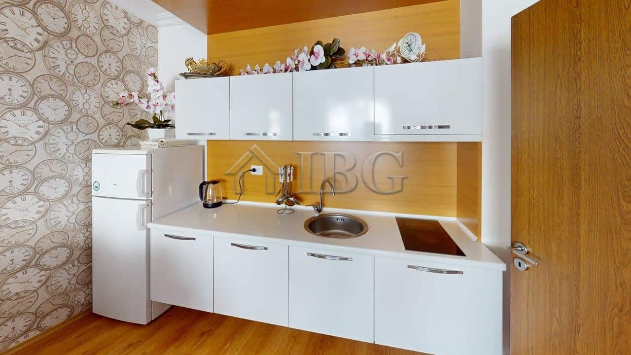 Bright, modern kitchen in Sunny Beach apartment with 2 rooms, featuring white cabinets and wooden ac.