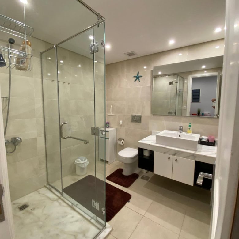 Spacious bathroom featuring a glass shower, white sink, and modern fixtures.