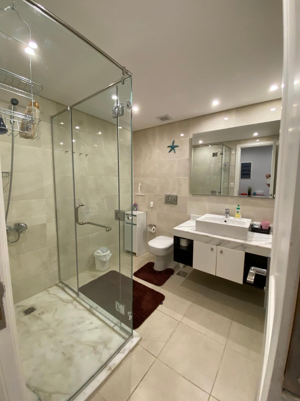 Spacious bathroom featuring a glass shower, white sink, and modern fixtures.
