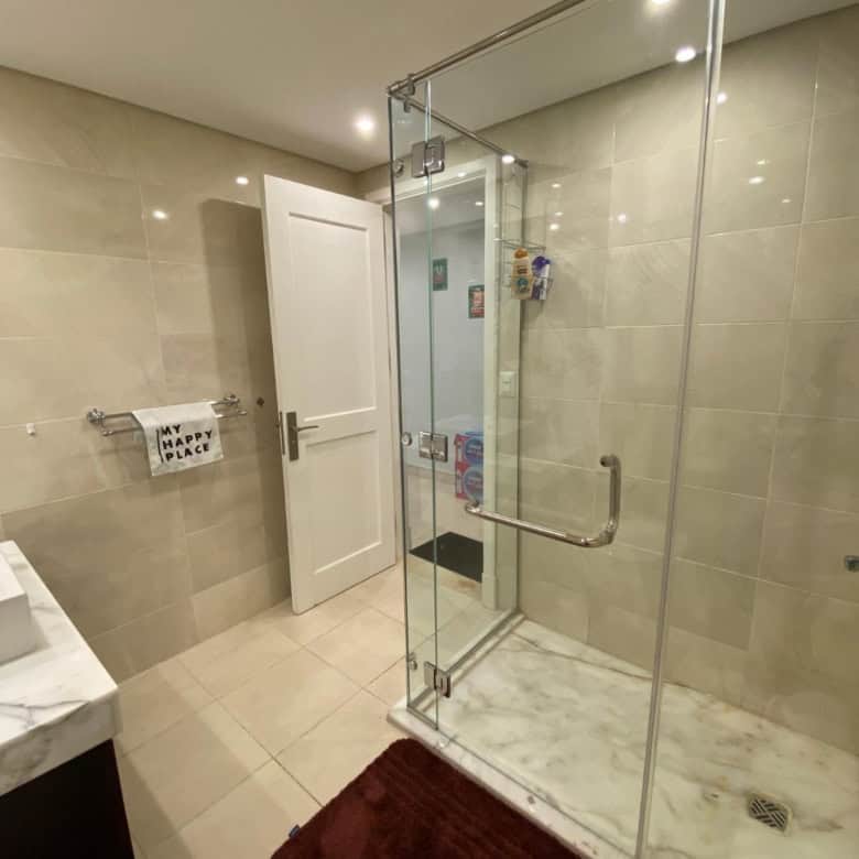 Modern bathroom with glass shower enclosure and beige tiled walls.