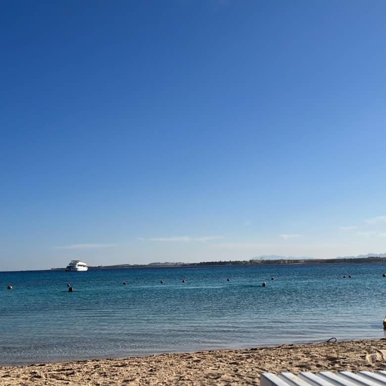 Beachfront property with stunning ocean views and boats in calm waters.