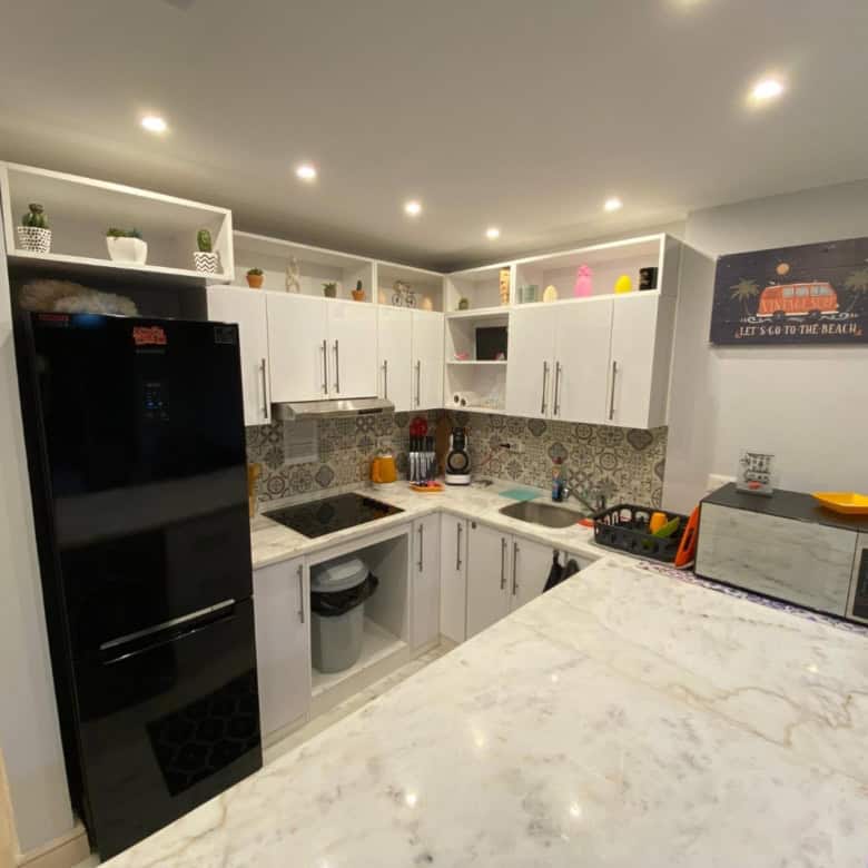 Modern kitchen with white cabinets, black refrigerator, and vibrant accents.