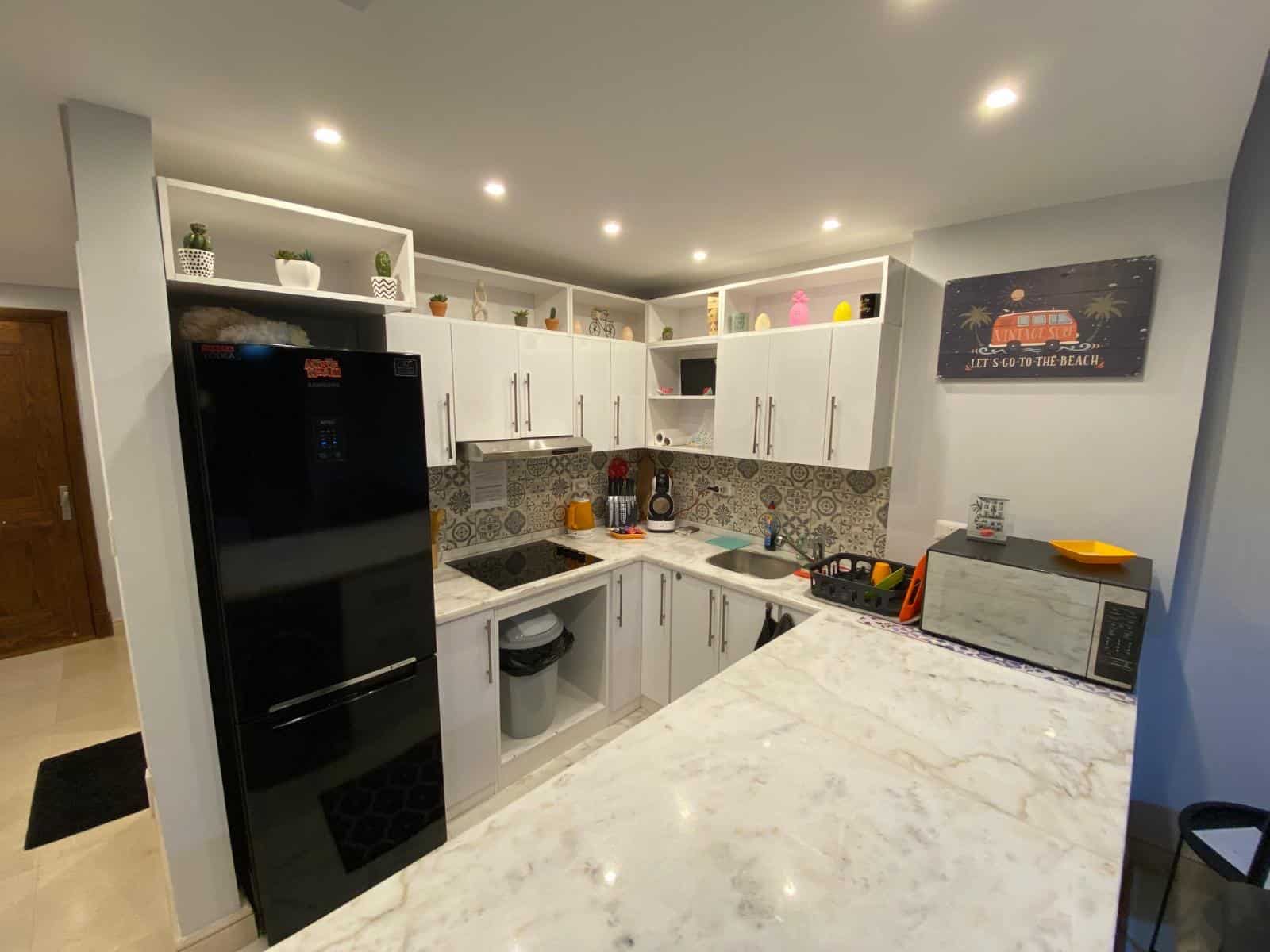 Modern kitchen with white cabinets, black refrigerator, and vibrant accents.