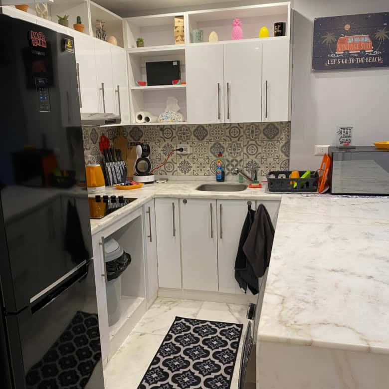 Modern white kitchen with black appliances and decorative backsplash.