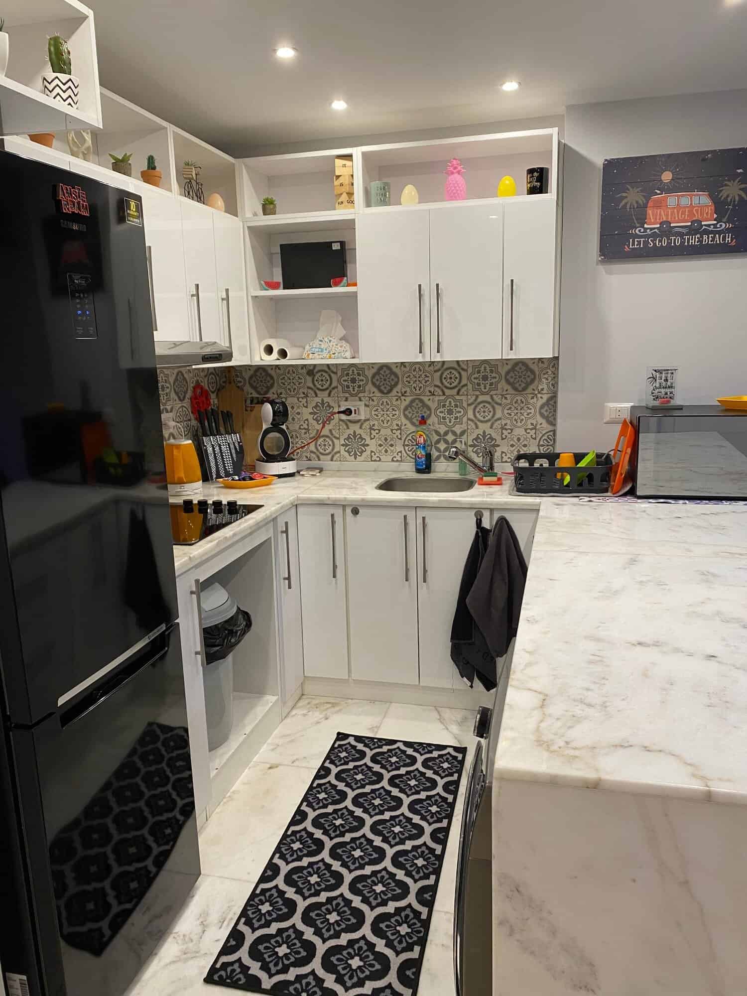 Modern white kitchen with black appliances and decorative backsplash.