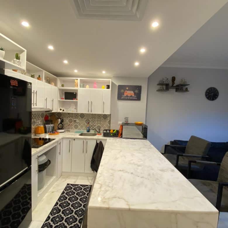 Modern white kitchen with marble island and seating area for family dining.