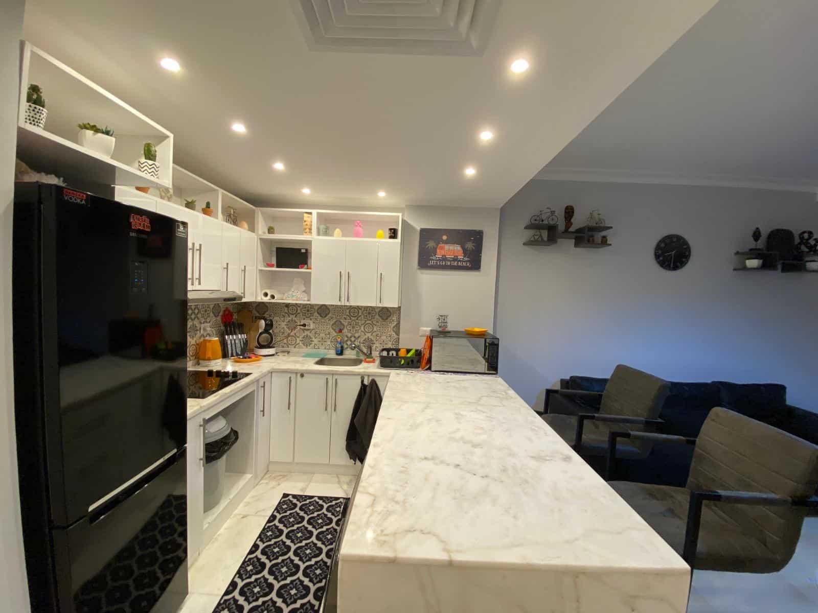 Modern white kitchen with marble island and seating area for family dining.