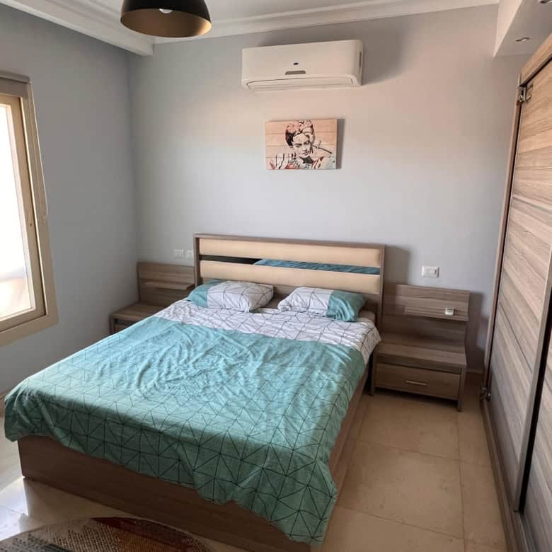 Comfortable bedroom with air conditioning, minimalist design, and contemporary artwork.