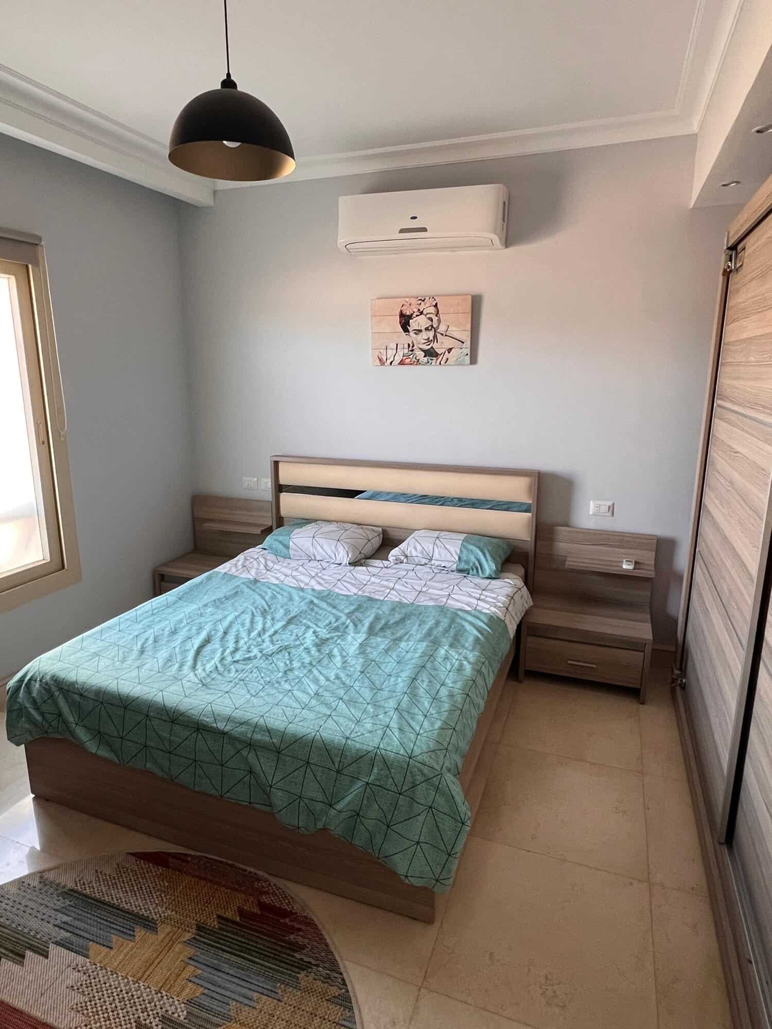 Comfortable bedroom with air conditioning, minimalist design, and contemporary artwork.