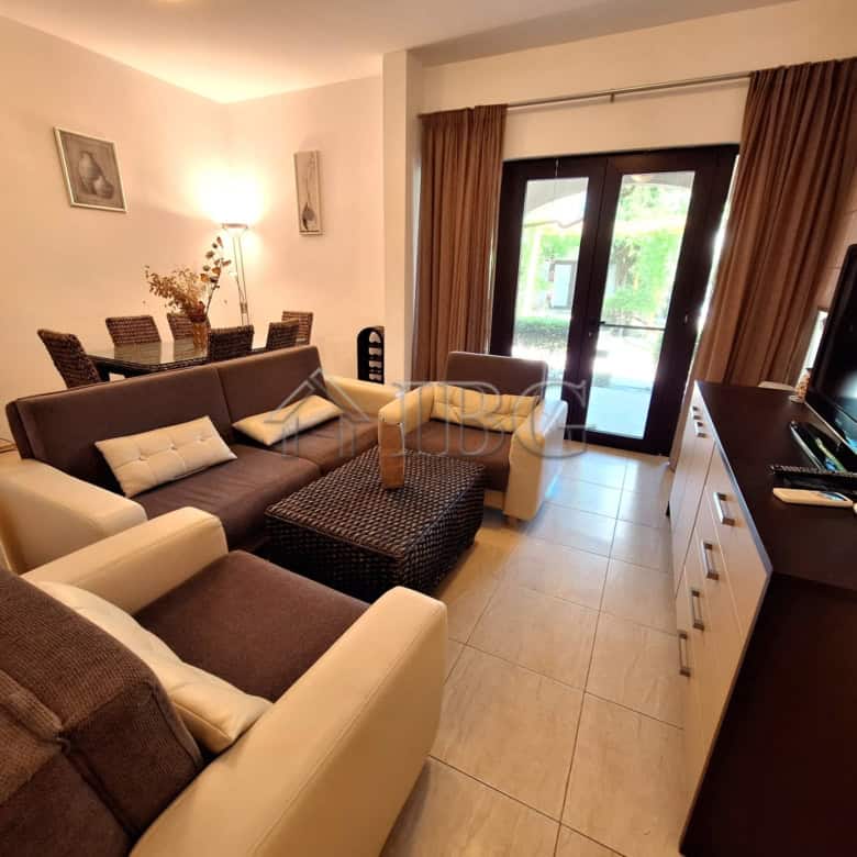 Bright living room with modern furniture and large windows overlooking the sea and park.