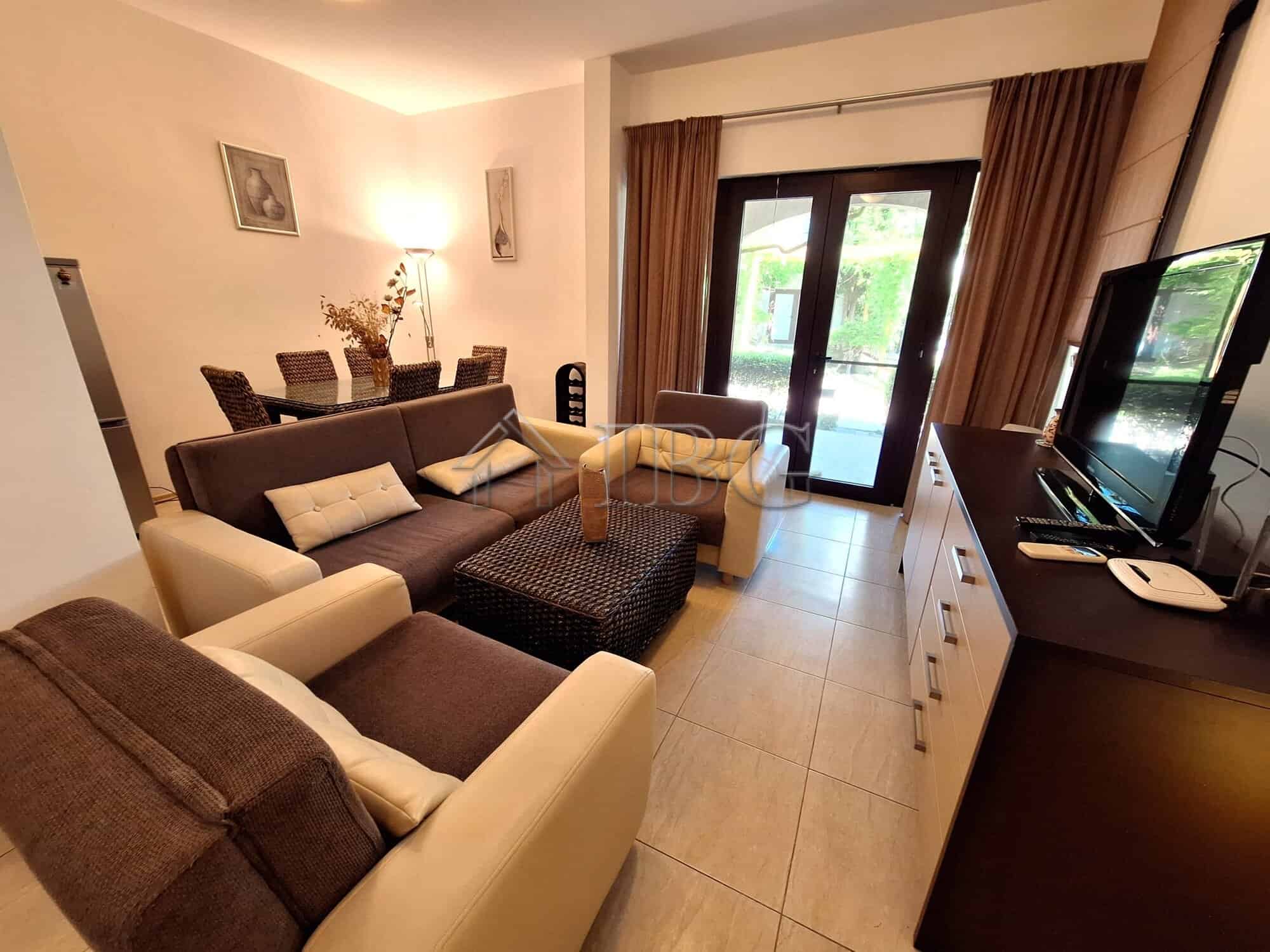 Bright living room with modern furniture and large windows overlooking the sea and park.