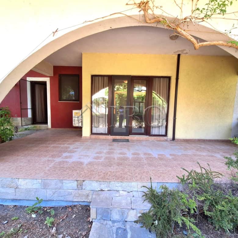 Ground-floor apartment with veranda, garden views, and sliding glass doors in a beachfront complex.