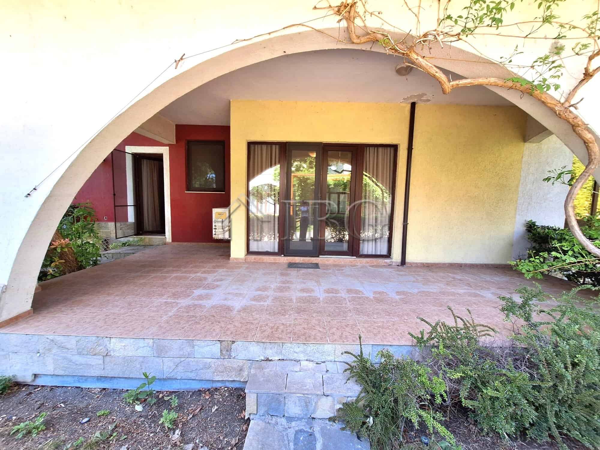 Ground-floor apartment with veranda, garden views, and sliding glass doors in a beachfront complex.