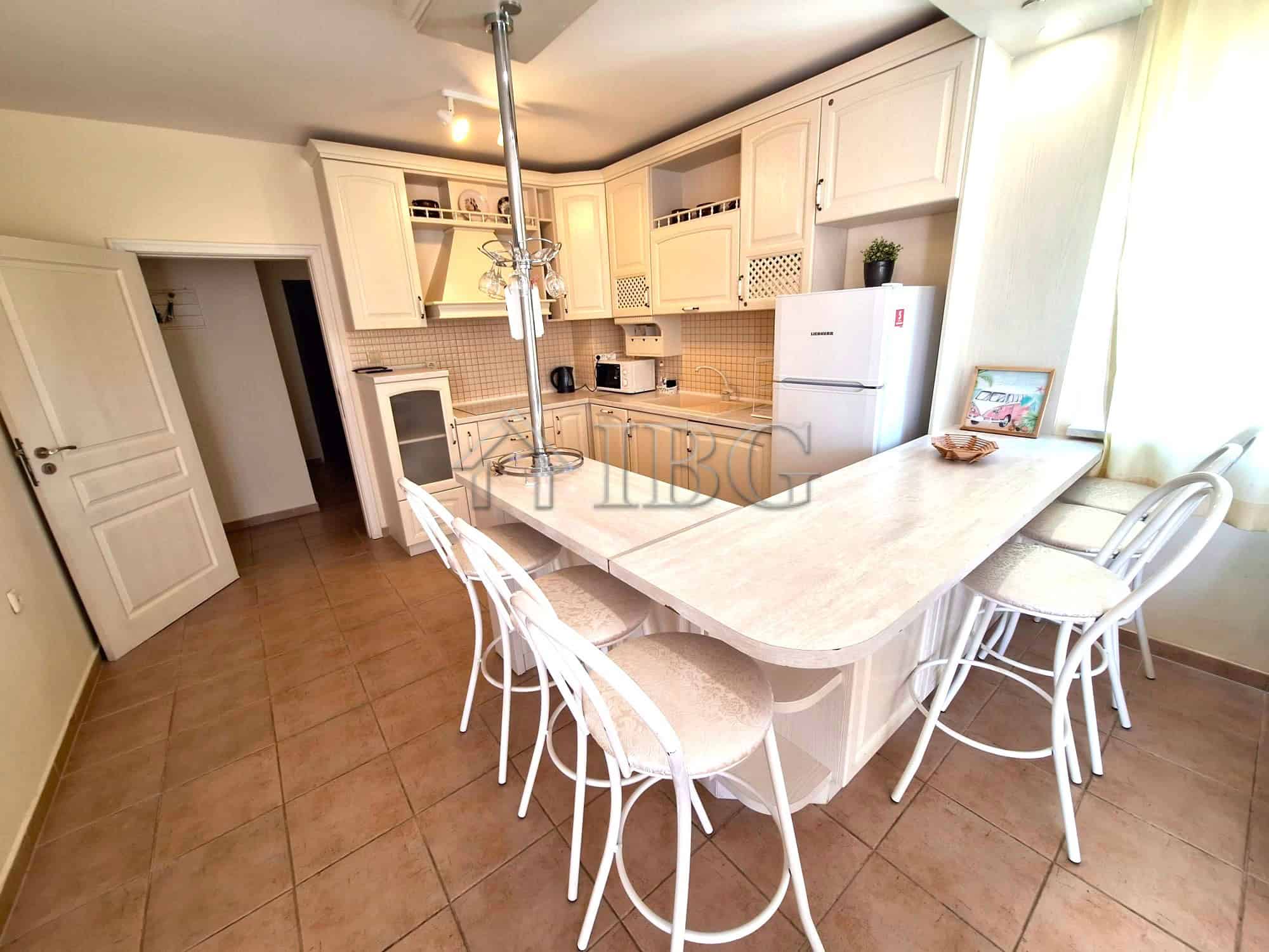Bright kitchen with white cabinets, breakfast bar, and seating for family meals.