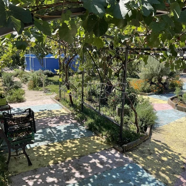 Beautiful garden space with seating and shaded areas near a renovated house.