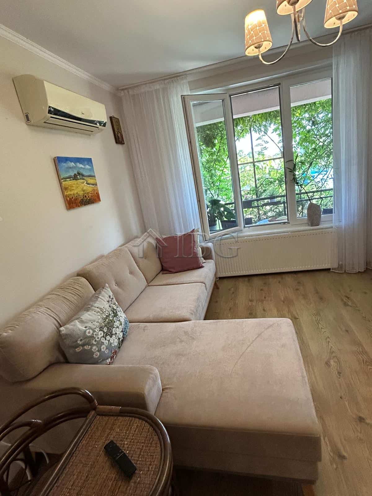 Bright living room with a large window overlooking greenery, featuring a comfortable beige sofa and.