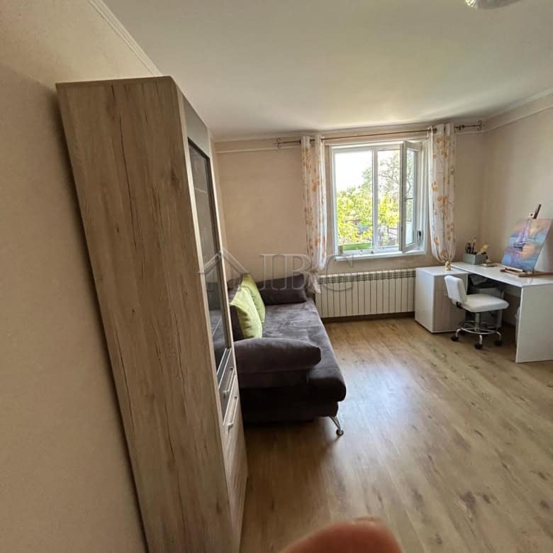 Living room with sofa and desk near window in renovated house.
