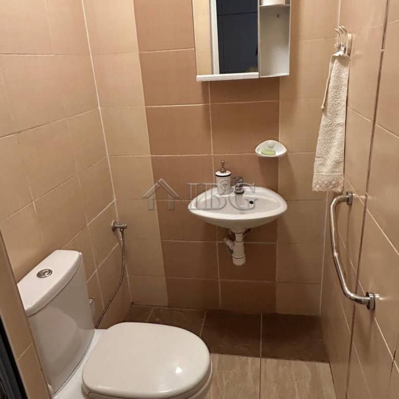 Small bathroom with toilet, sink, mirror, and towel rail in a renovated house near the sea.