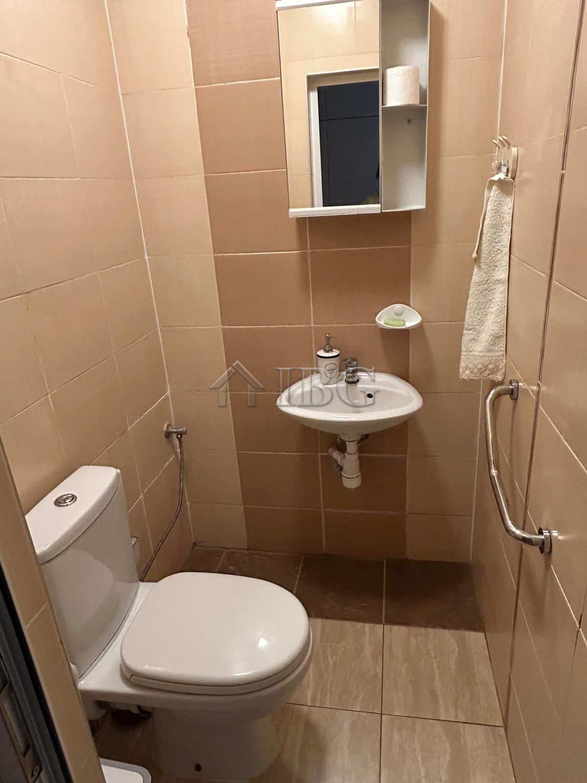 Small bathroom with toilet, sink, mirror, and towel rail in a renovated house near the sea.