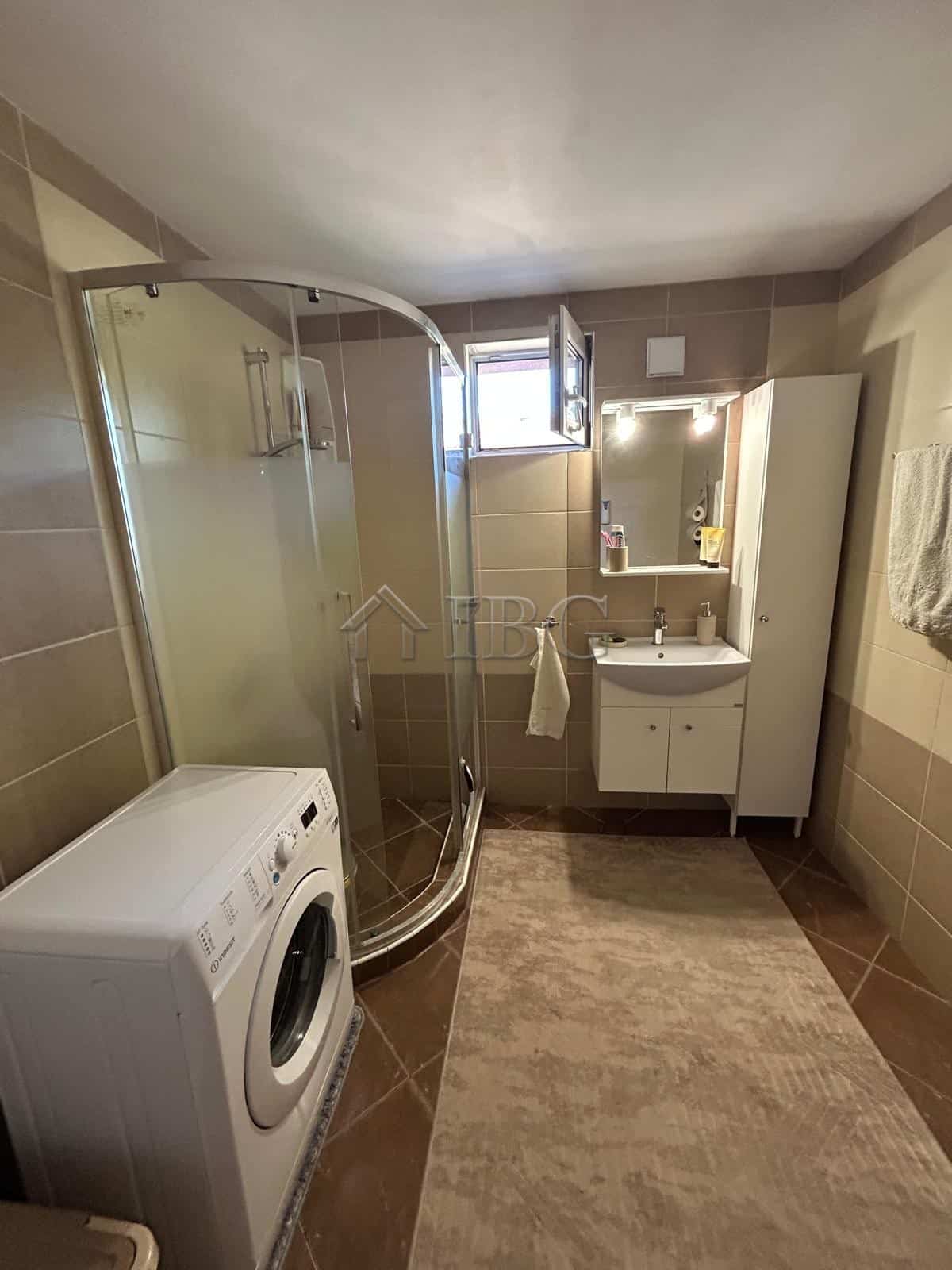 Bright bathroom with shower, washing machine, and vanity in a quiet residential area.