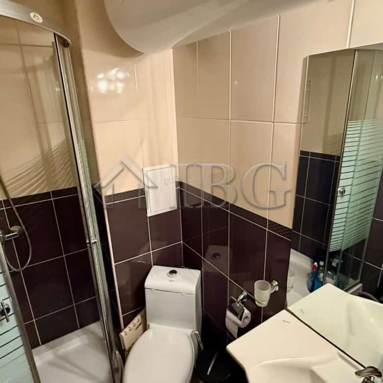 Bright bathroom featuring a shower enclosure, toilet, and sink with mirror.