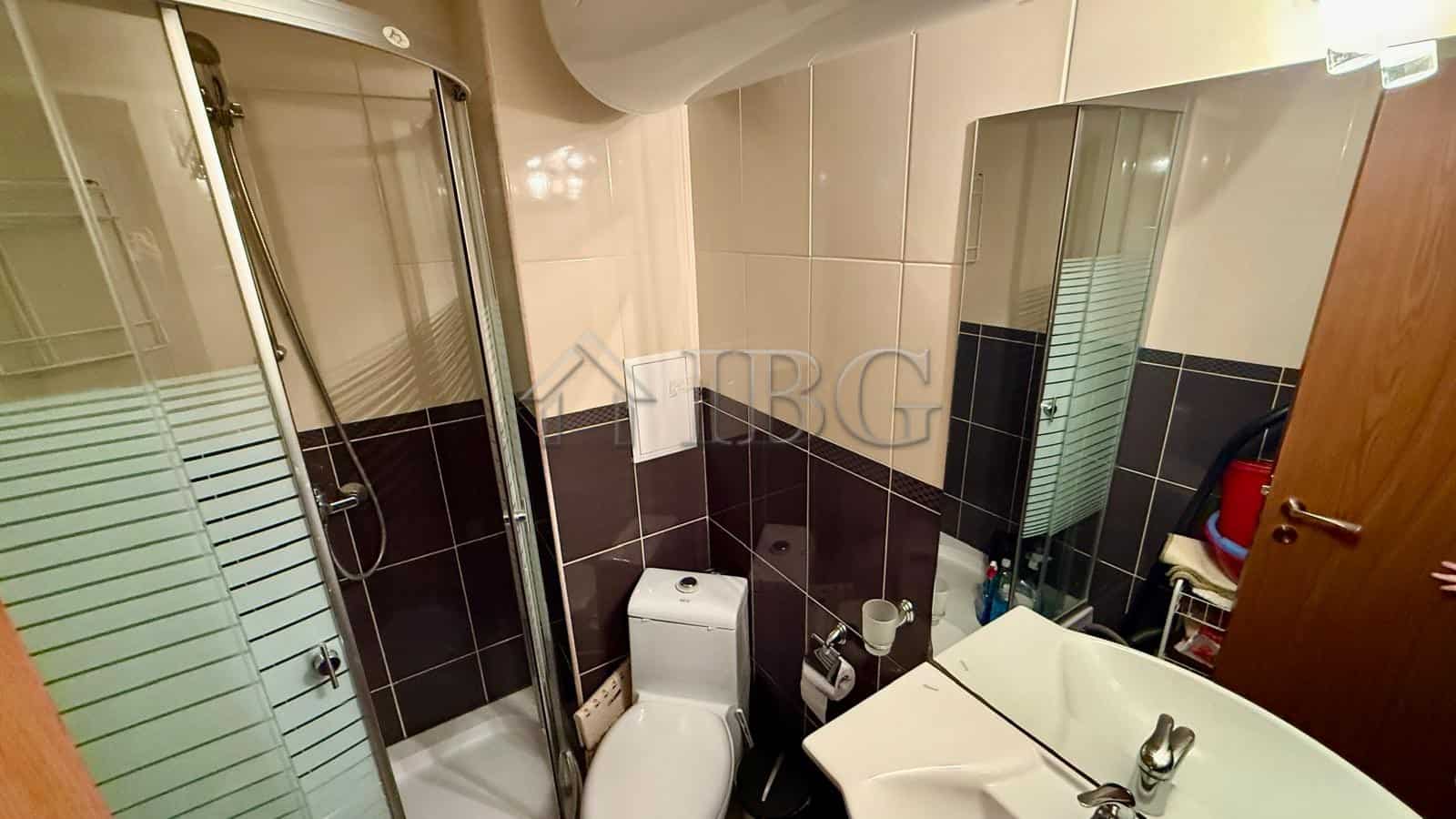 Bright bathroom featuring a shower enclosure, toilet, and sink with mirror.