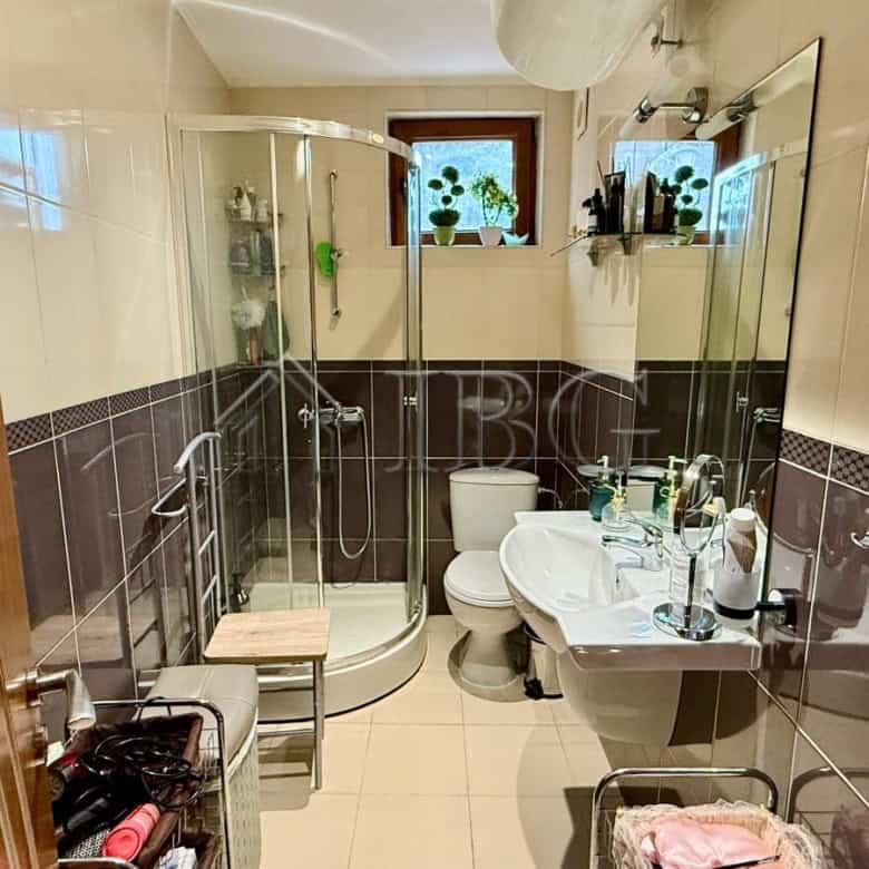 Bright bathroom featuring a glass shower enclosure, toilet, and vanity with mirror.