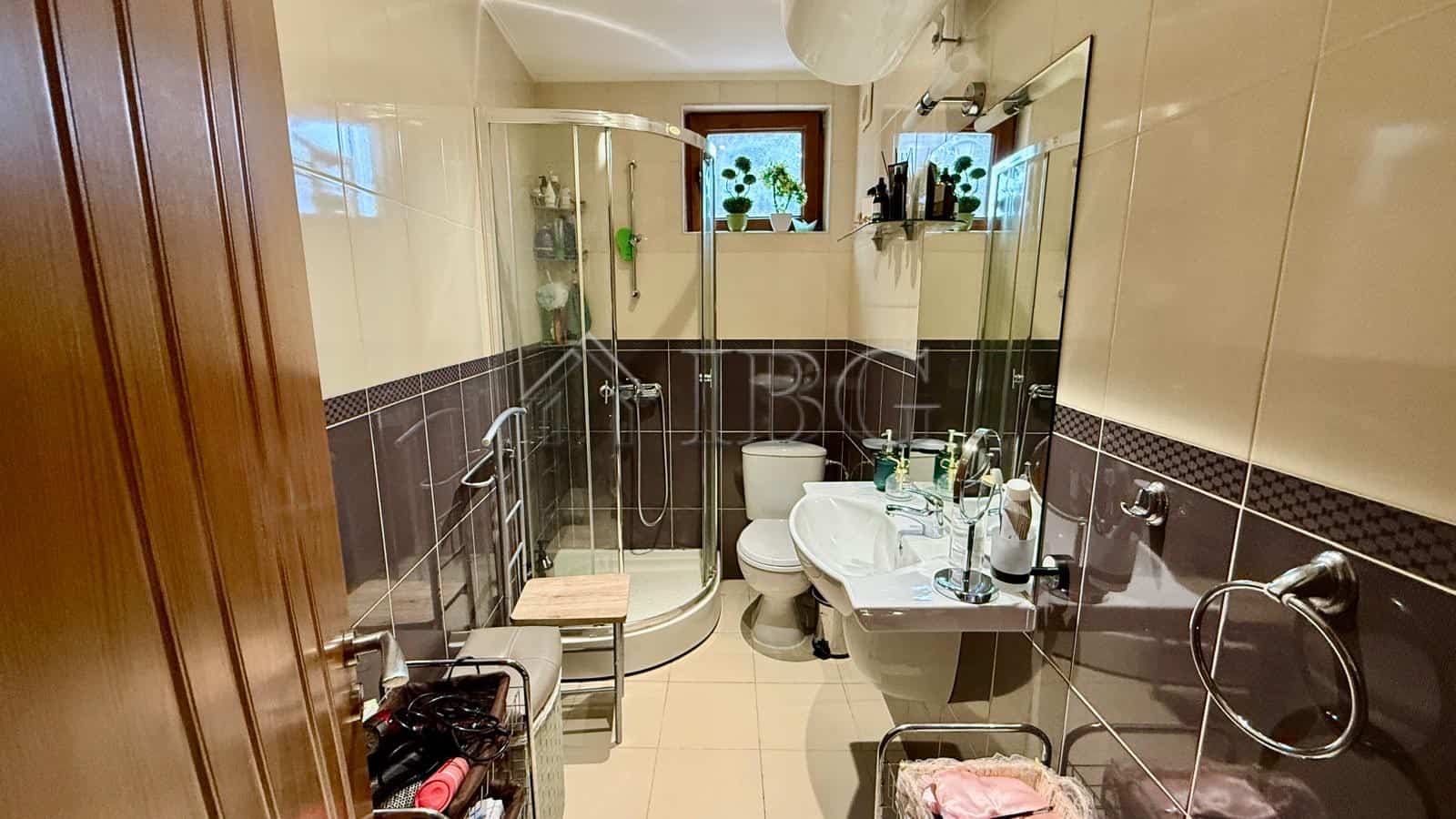 Bright bathroom featuring a glass shower enclosure, toilet, and vanity with mirror.