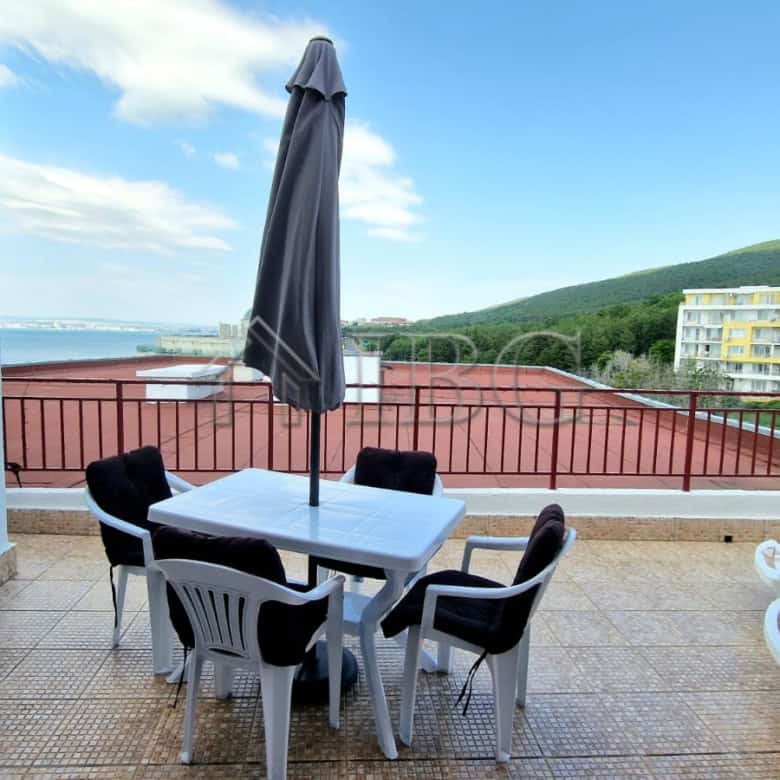 Outdoor terrace with sea view, table, chairs, and umbrella in Sveti Vlas.